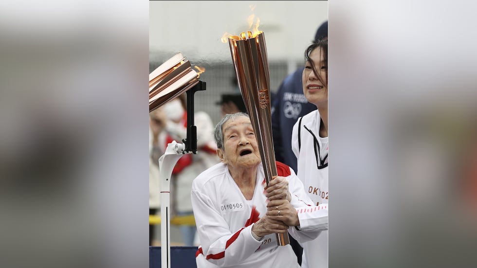 Shigeko Kagawa holds a torch during a torch relay event for the Tokyo Olympics in...