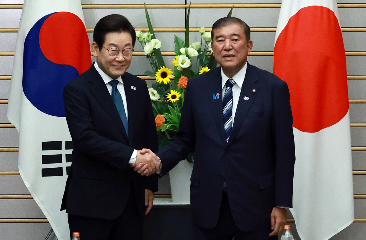 President Lee Jae Myung (left) and Japanese Prime Minister Shigeru Ishiba shake hands during a summit held at Ishiba's official residence in Tokyo on Saturday. (Yonhap)