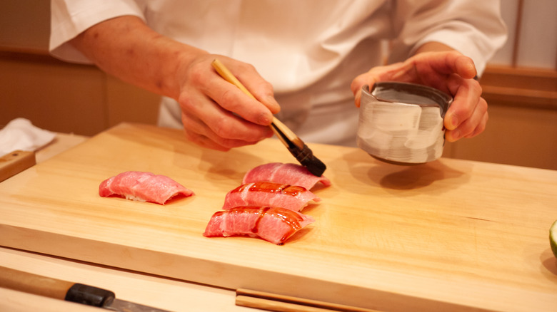 Sushi chef painting sauce on nigiri