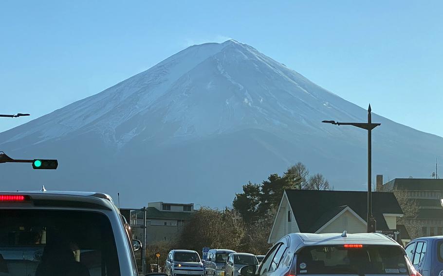 A mountain against a hazy blue sky is seen in the distance, with cars on a street in the foreground.
