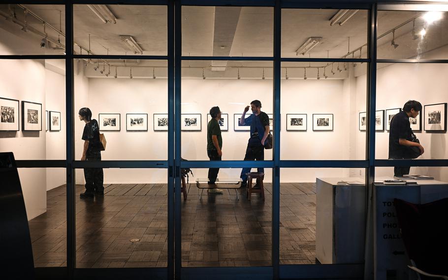 People are seen through a wall of glass, looking at a photography museum display.