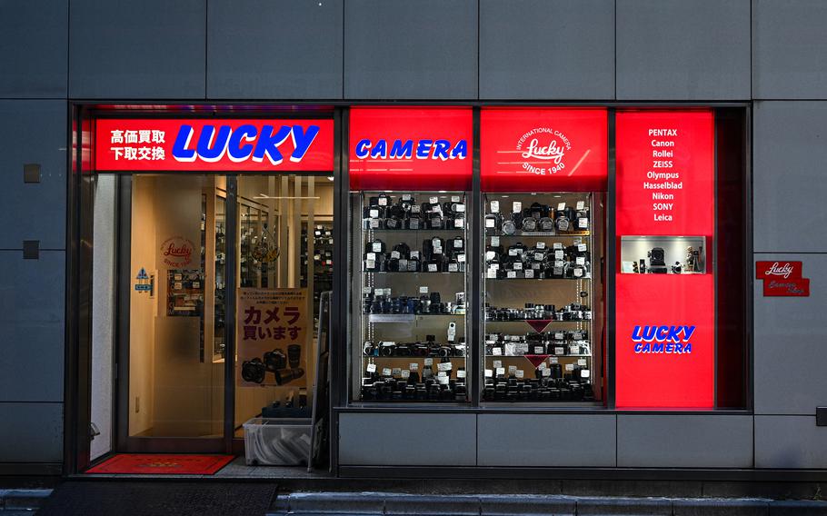 A shop interior containing camera supplies is lit up at night.