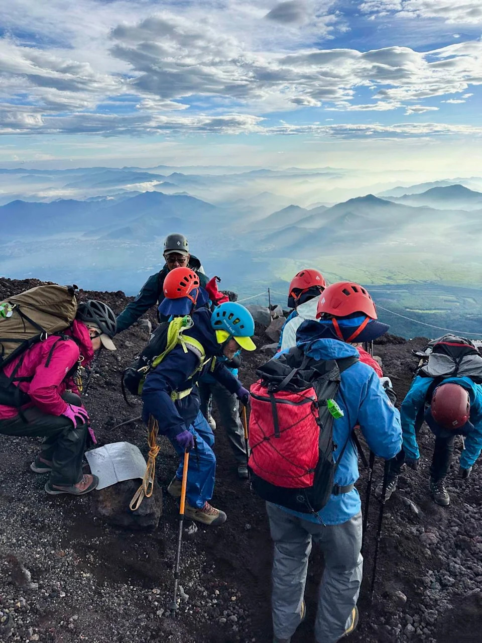 This photo provided by Motoe Hoshino shows her father Kokichi Akuzawa, center in a blue helmet, as they and their climbing friends and other family members were climbing Mount Fuji, west of Tokyo, Aug. 5, 2025. (Family courtesy photo via AP) (Akuzawa family courtesy photo)