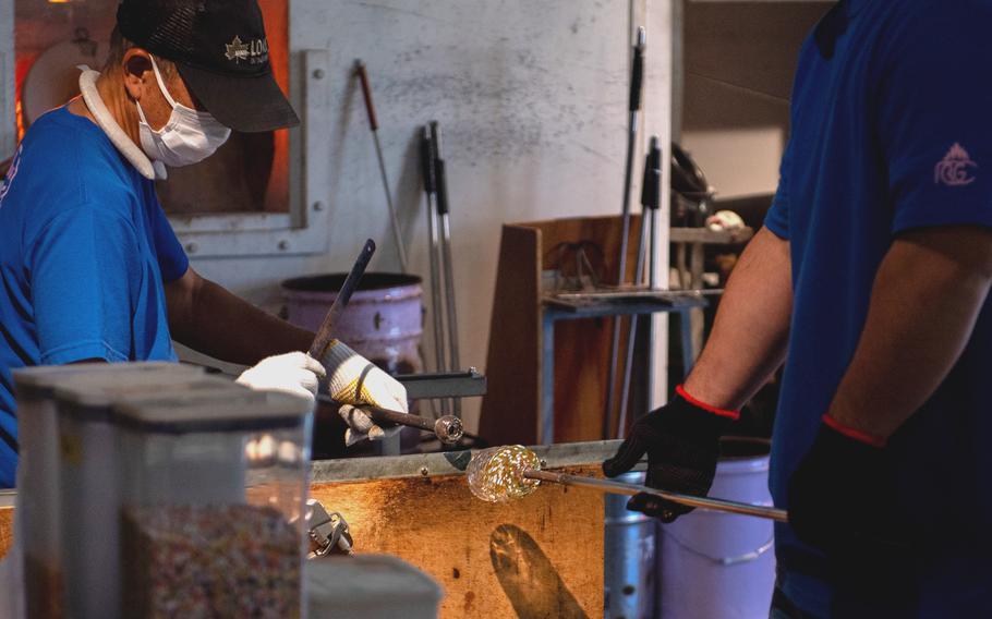 A glass craftsman shapes a creation in progress.