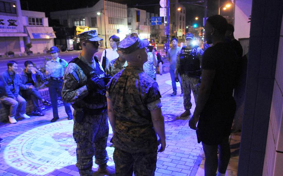Col. David Banning talks to off-duty service members on a dimly lit street at night.
