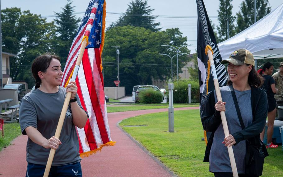 U.S. Air Force Senior Airman Samantha White, left, 374th Airlift Wing public affairs specialist, and Tomoko Kobayashi, 374 AW public affairs administrator, hold the U.S. and POW/MIA flags.