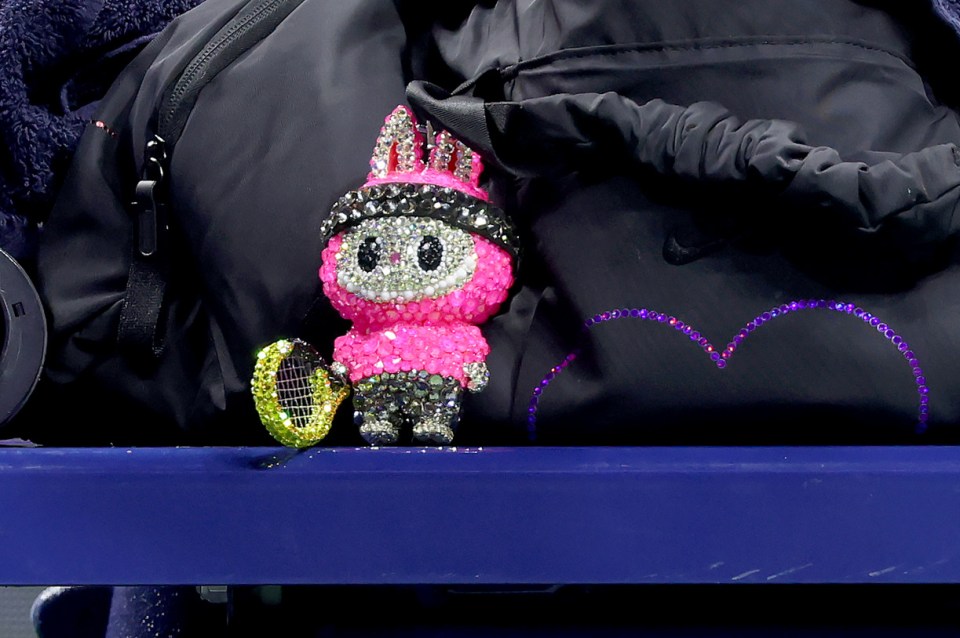 Rhinestone-covered Labubu doll with miniature tennis racquet.