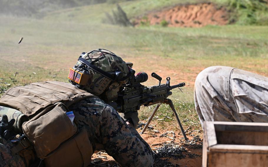 A Marine in prone firing position aims a bipod-mounted gun during field training exercises. 