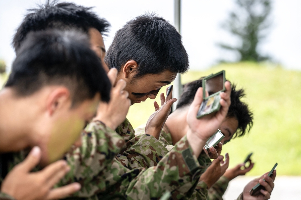 Members of the Japan Ground Self-Defence Force (JGSDF) putting on camouflage face paint during an exercise at JGSDF Camp Naha in Okinawa Prefecture June 9, 2025. — AFP pic