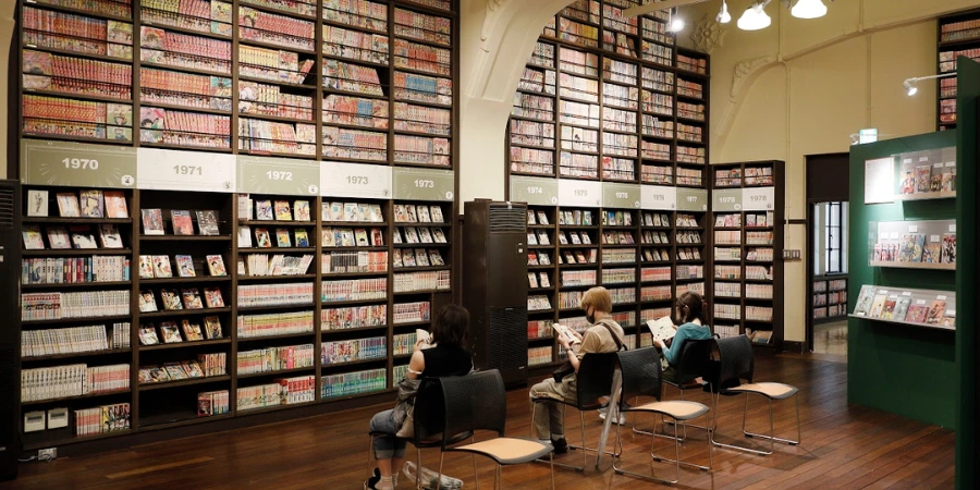 three people sitting in front of the Wall of Manga, each reading their manga of choice