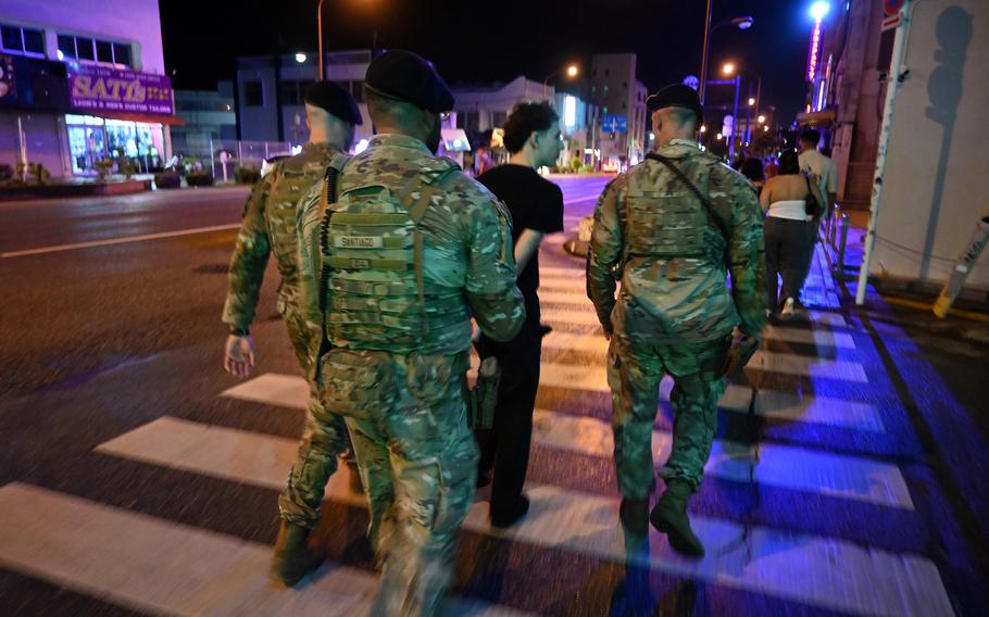 Members of the 18th Security Forces Squadron walk with a detained service member.