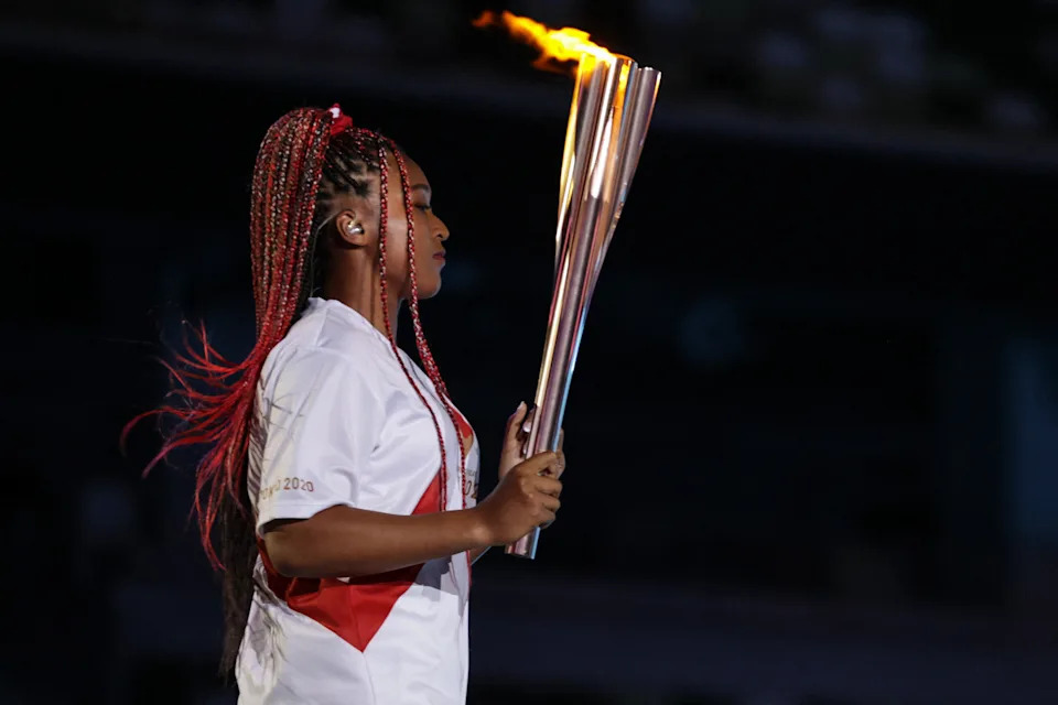 Japan's tennis player Naomi Osaka carries the Olympic Torch before lighting the flame of hope in the Olympic Cauldron during the opening ceremony of the Tokyo 2020 Olympic Games, at the Olympic Stadium, in Tokyo, on July 23, 2021. (Photo by HANNAH MCKAY / POOL / AFP) (Photo by HANNAH MCKAY/POOL/AFP via Getty Images)