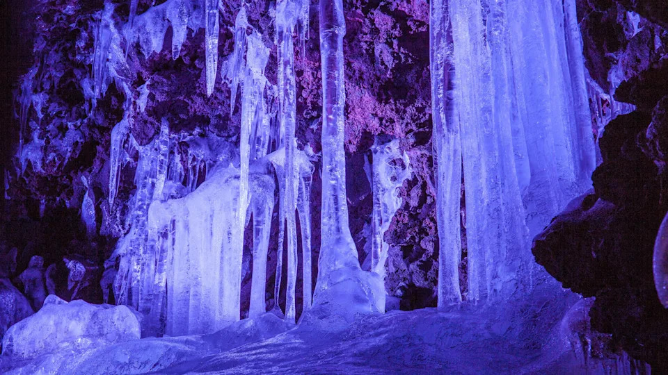 Ice pillars inside the Narusawa Ice Cave. The cave is illuminated with blue light.