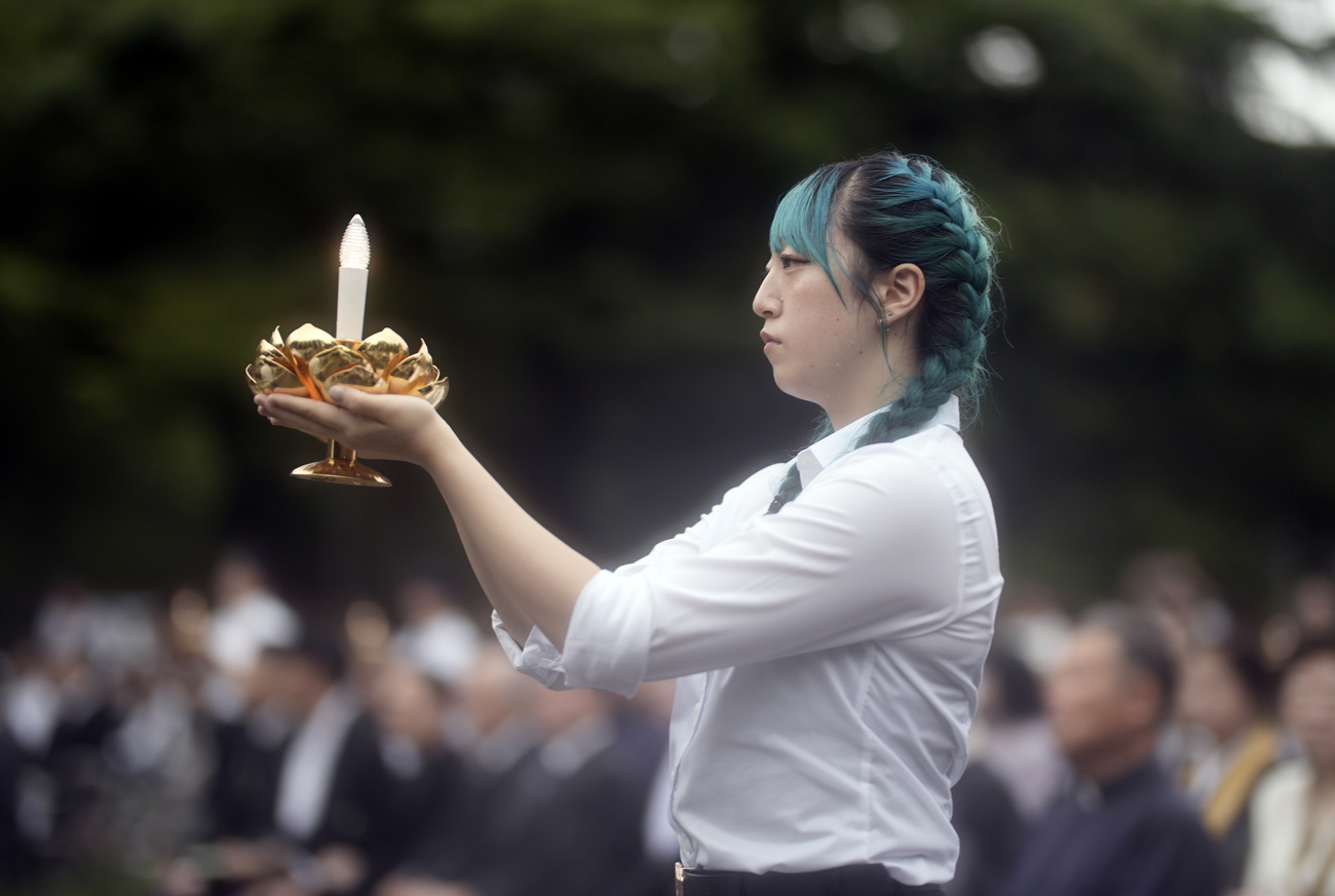 A young student holds a candle at the start of a memorial ceremony for the victims of the atomic bomb at the Hypocenter Park in Nagasaki, southwestern Japan, 08 August 2025.