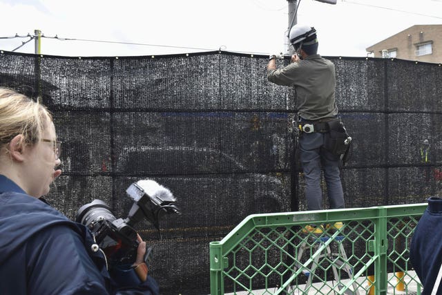 A worker setting up the black screen on a stretch of pavement 