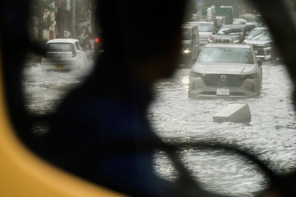 Vehicles drive through a flooded road caused by heavy rain Thursday, Sept. 11, 2025, in Tokyo. (AP Photo/Eugene Hoshiko)