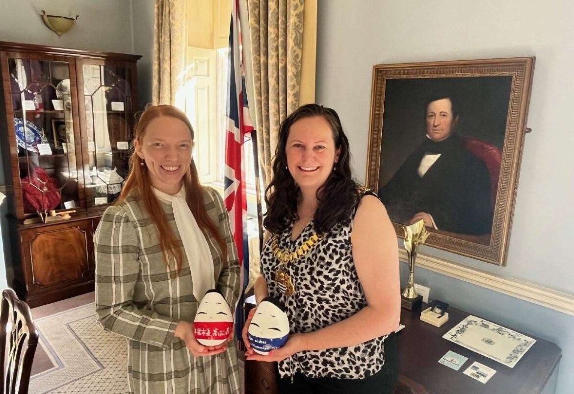Newark native Aimee Brown presents Newark Mayor with Okiagari-koboshi dolls, a traditional gift from Motomiya in the Aizu region of Fukushima, Japan