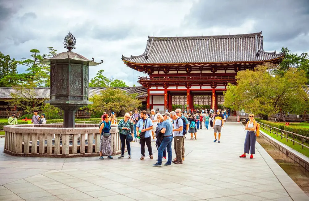 InsideJapan tour leader and group in Nara in front of temple.