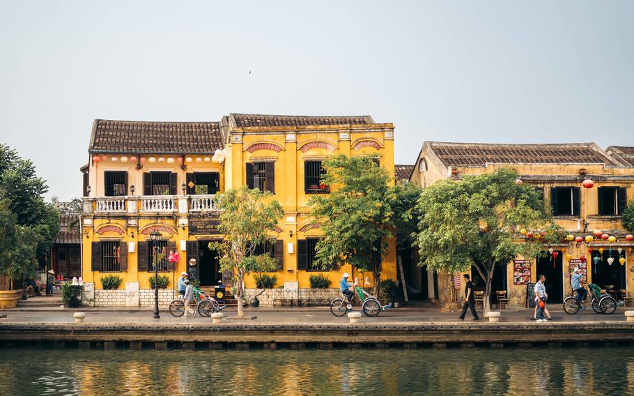 A river, some buildings, and people on the street.
