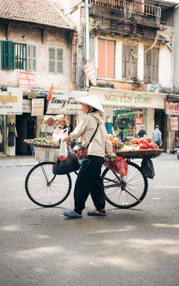 A peddler sells vegetables on a bike in Old Quarter Street.