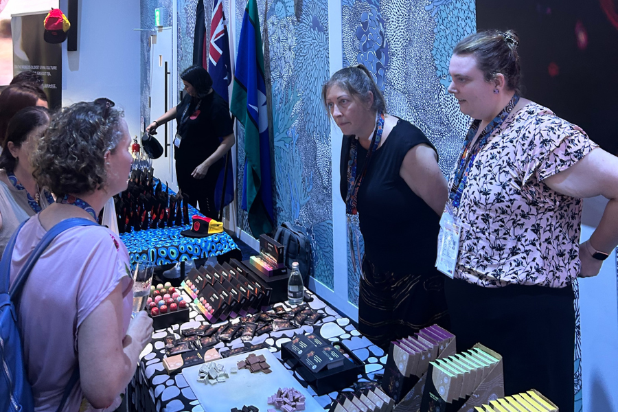 Visitors browsing various products at a trade show booth of a First Nations Business. 