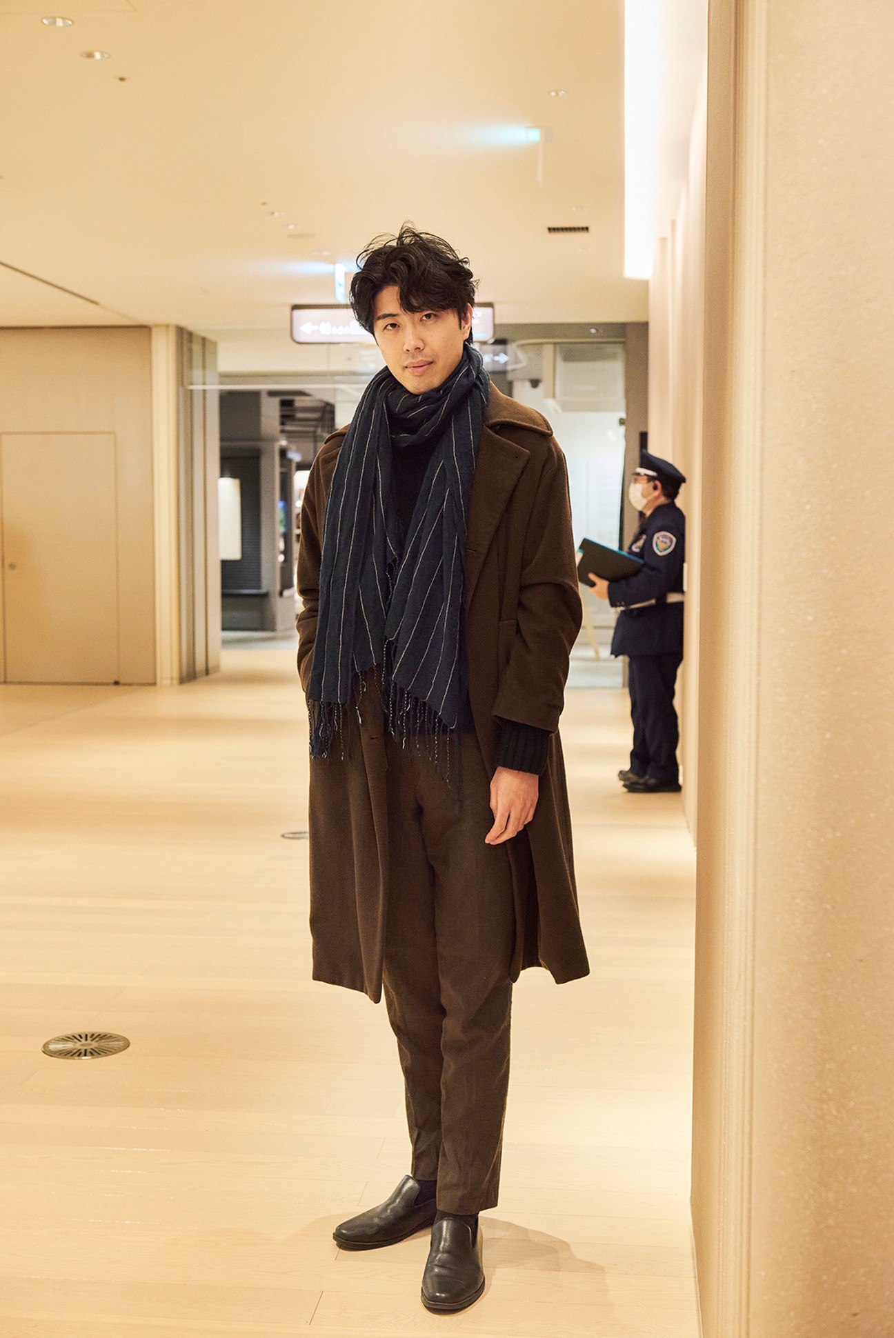 Man in a coat posing indoors in a chic retail environment