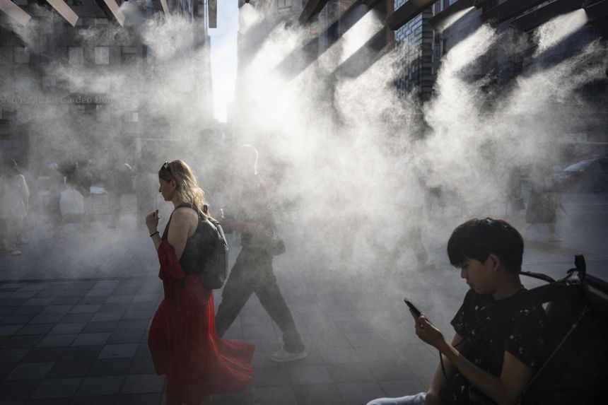 People walk underneath a water misting system to cool down on a hot day in Tokyo, Japan on September 6, 2025.