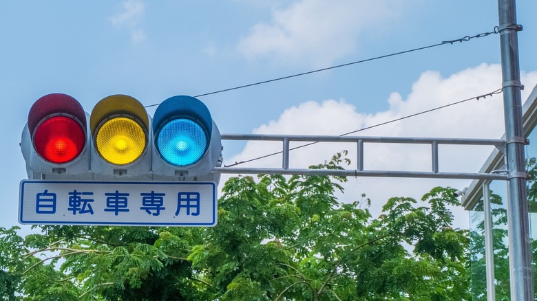 A blue-green traffic light attached to a pole in Japan