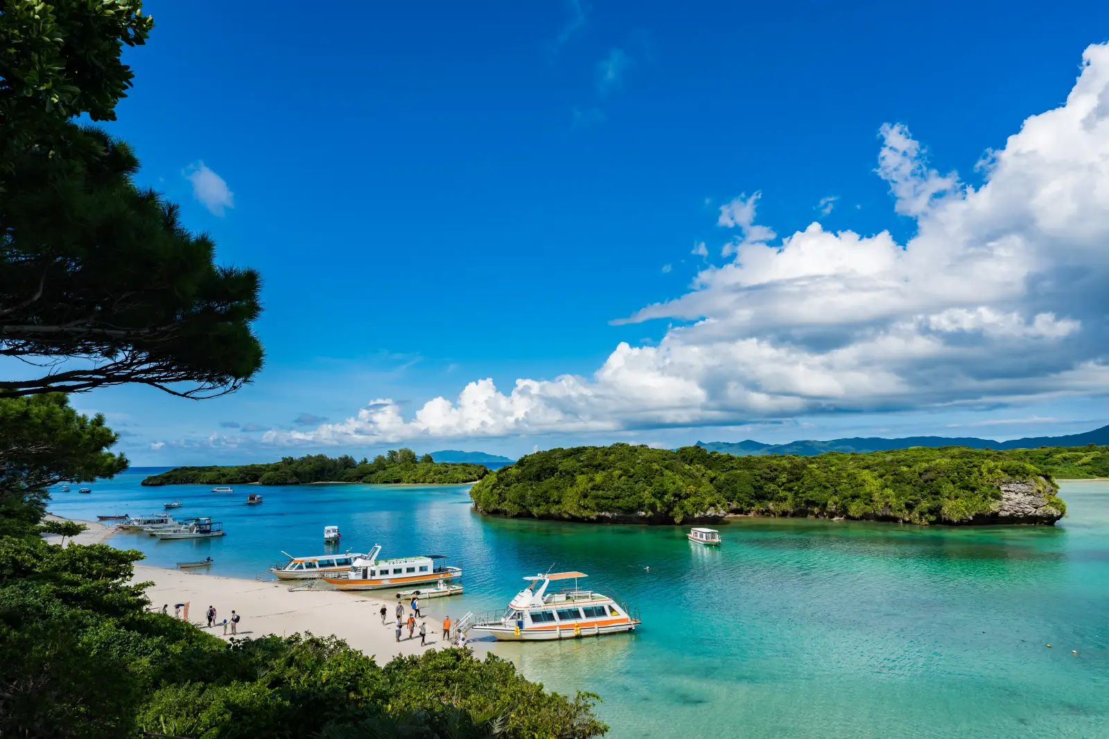 Tour boats docked along Kabira Bay with turquoise waters and green islands in Ishigaki, Okinawa, Japan