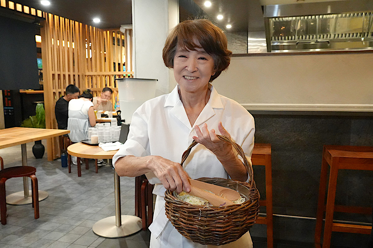 japanese lady offers a basket of shredded Cabbage inside restaurant