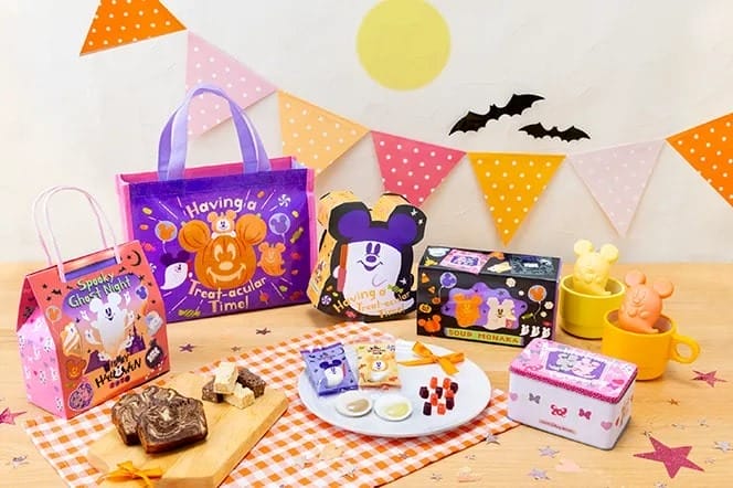 Colorful 2025 Halloween Merchandise from Tokyo Disney Resort—festive treats, mugs, bags, and tins on a decorated table.
