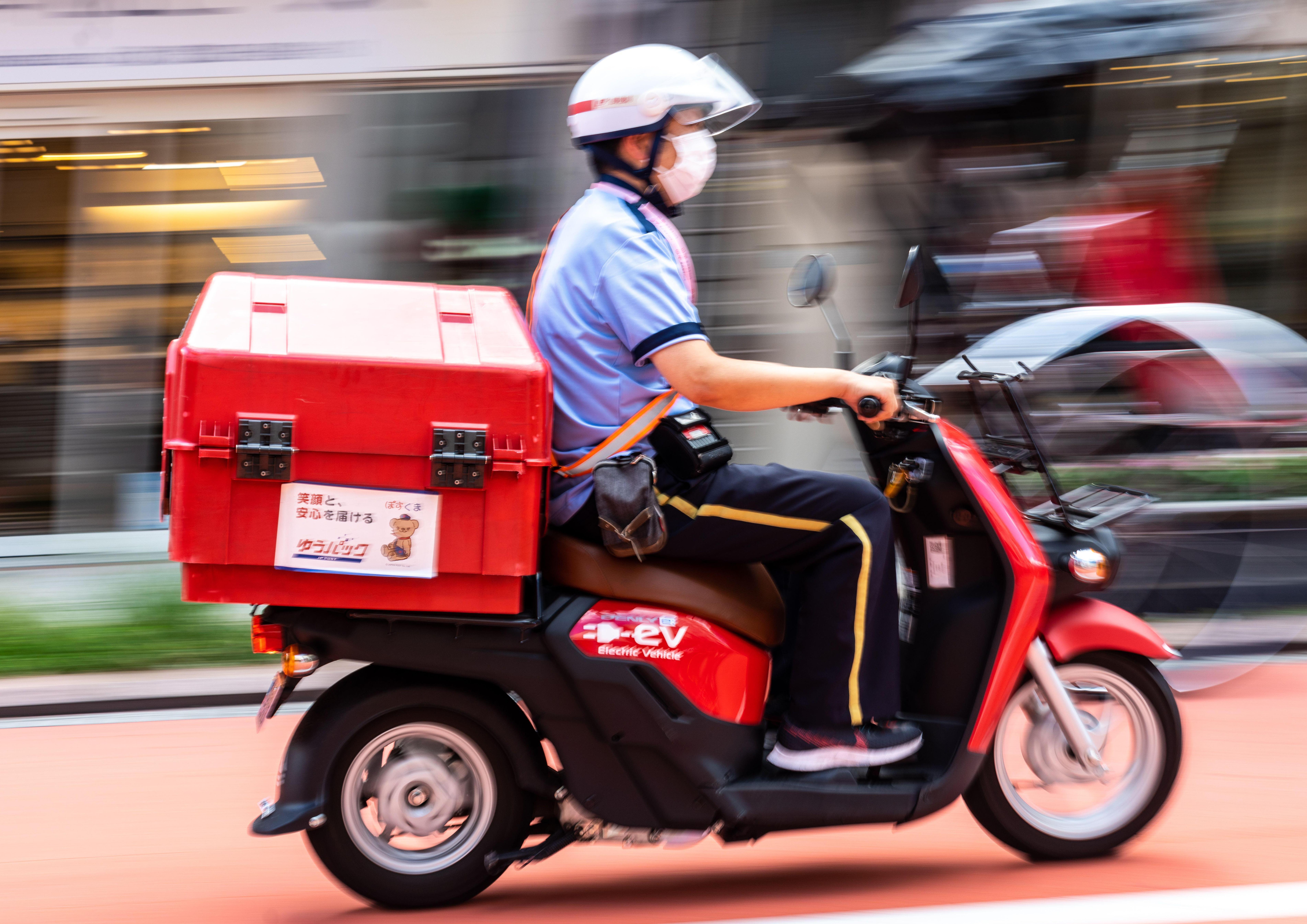 A Japanese postal worker delivers mail by electric delivery scooter near the Sensoji temple in Asakusa, Tokyo.