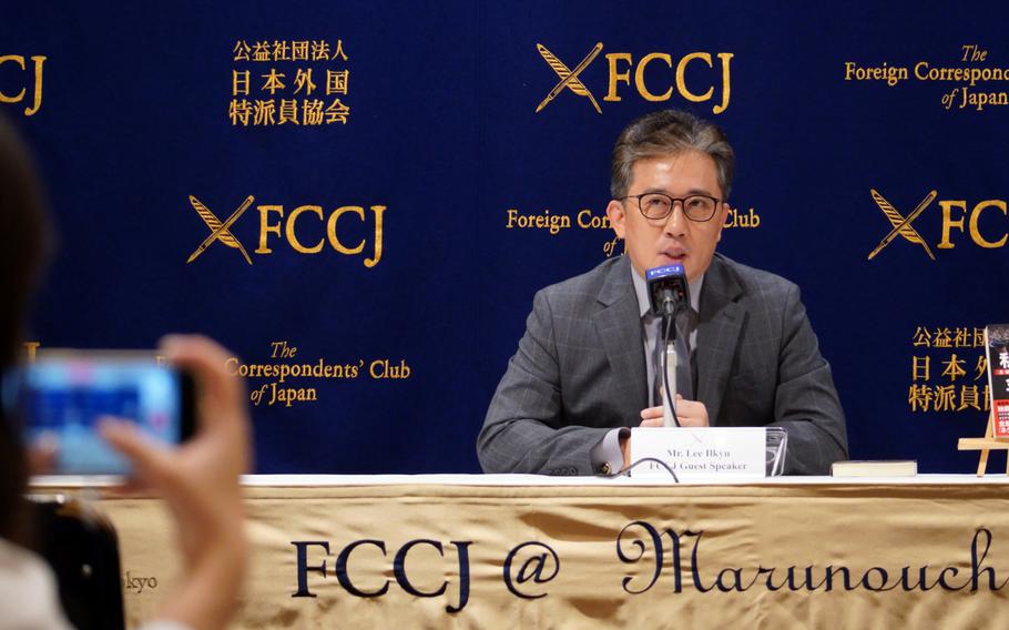A man in glasses speaks into a microphone.