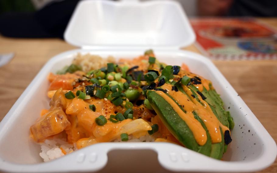 A styrofoam to-go box is full of bright, fresh-looking vegetable-topped food.