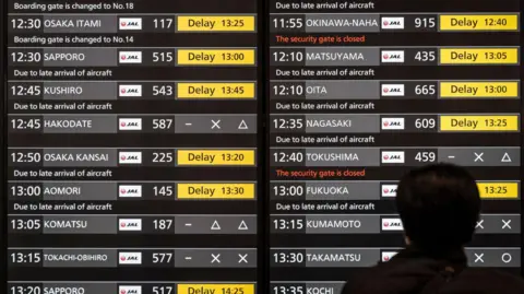 AFP via Getty Images A man looks at a screen showing the delay of Japan Airlines flights at the departures hall of Haneda Airport in Tokyo on December 26, 2024. Japan Airlines on December 26 reported a cyberattack that caused delays to domestic and international flights but later said it had found and addressed the cause. 