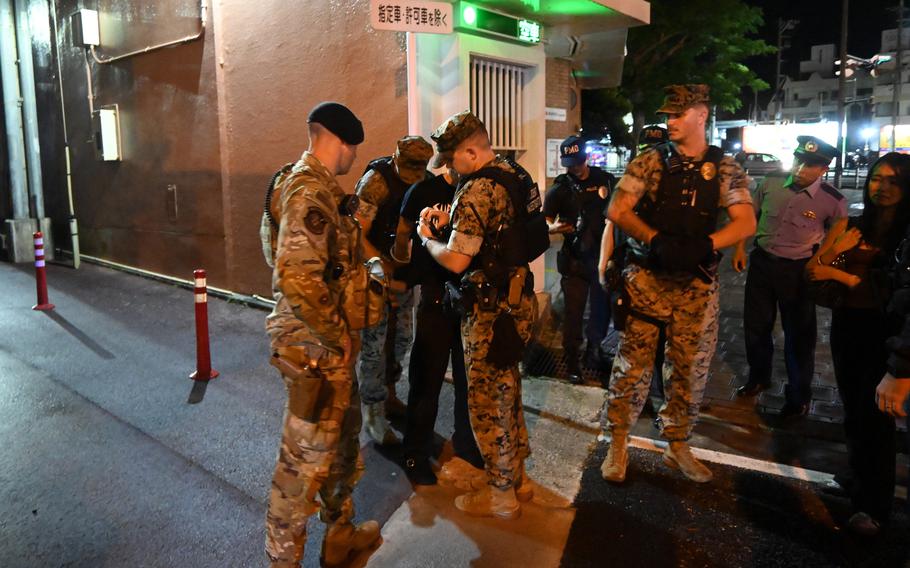 U.S. military police detain a service member during a joint patrol of Gate 2 Street in Okinawa city, Okinawa, Sept. 27, 2025.