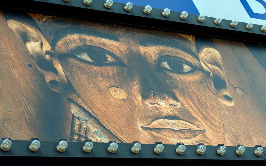 A close-up of a sign shows an image of an Egyptian sarcophagus.