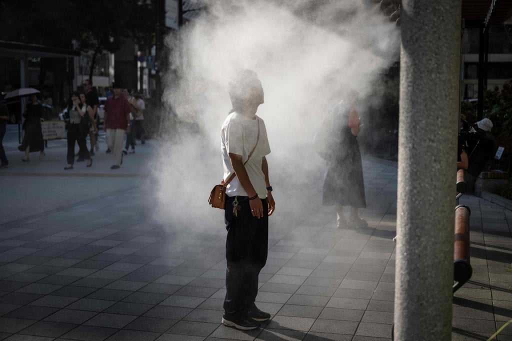 A man standing under a water misting system to cool down on a hot day in Tokyo. Photo: AFP