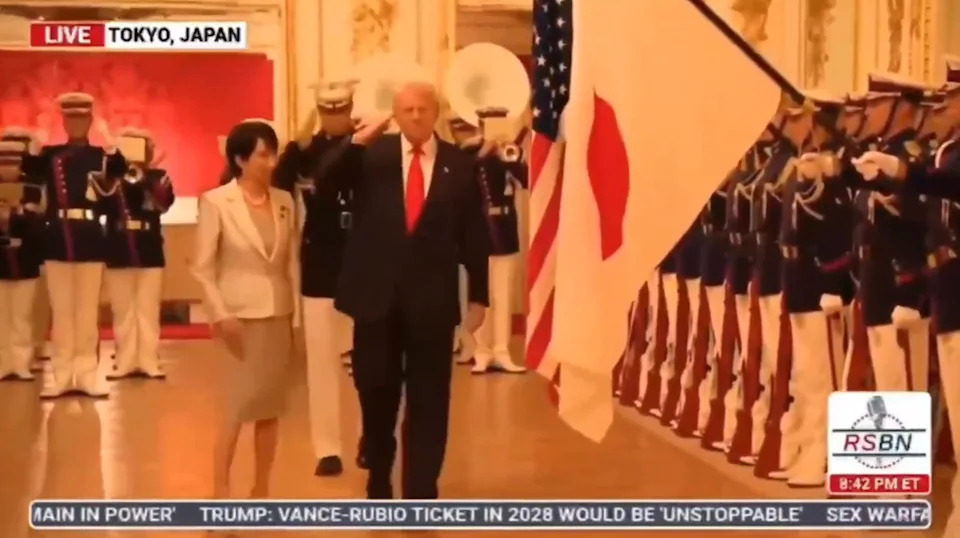 A formal event in Tokyo, Japan with two people walking past a row of uniformed guards holding Japanese and U.S. flags