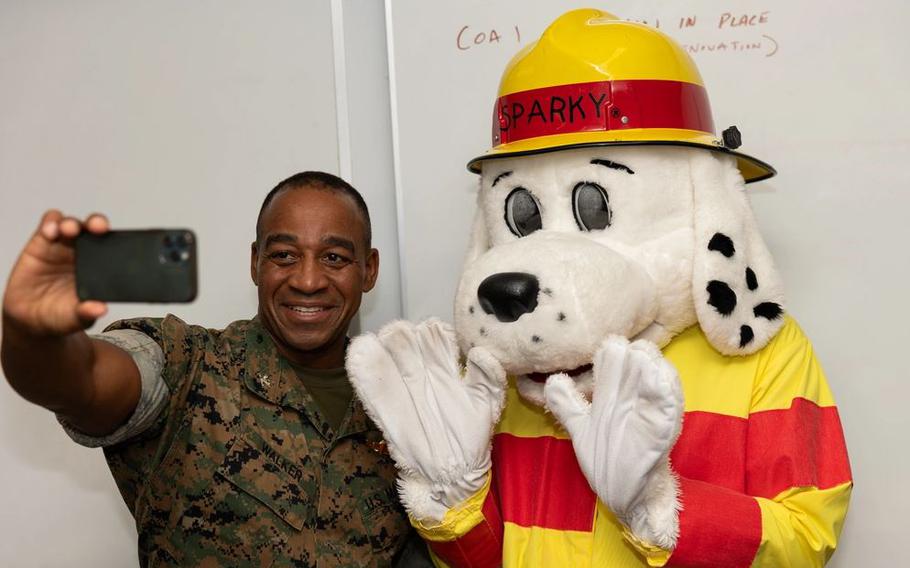 U.S. Marine Corps Col. Marc Walker, commanding officer of Headquarters and Support Battalion, Marine Corps Installations Pacific, takes a photo with Sparky the Dog, the mascot of the National Fire Protection Association.