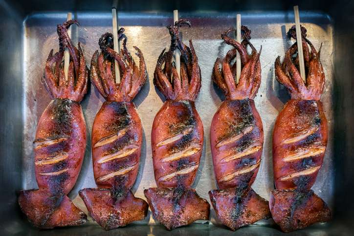 Freshly grilled whole squid on skewers, a popular street food sold near Enoshima’s beachfront and shrines.