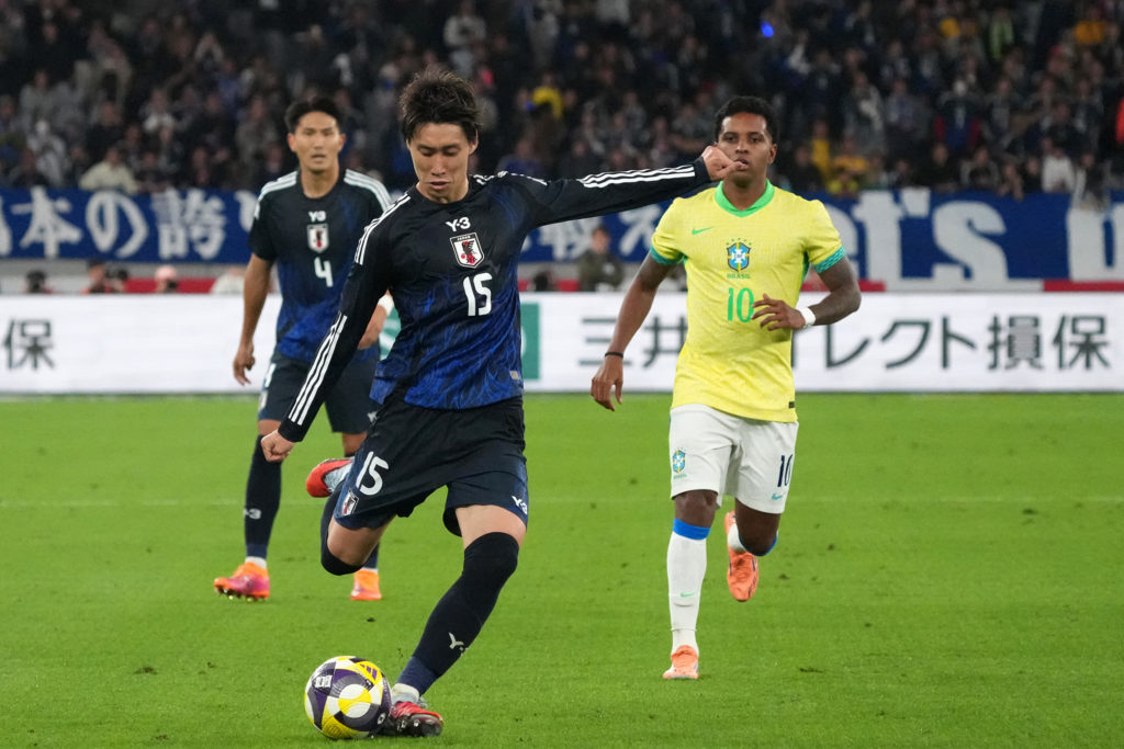 Daichi Kamada of Japan (C) controls the ball against Rodrygo of Brazil (R).