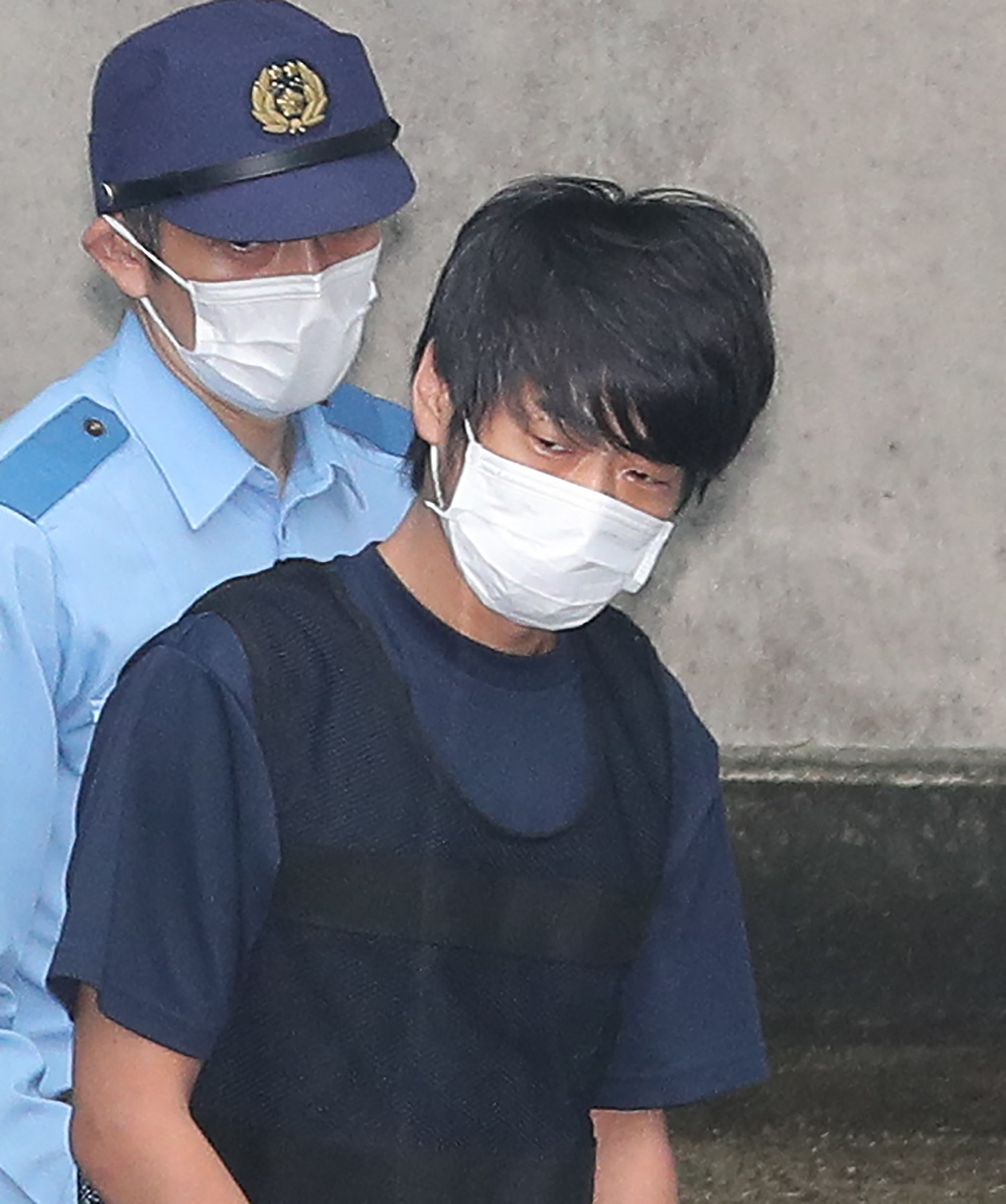 This photo taken on July 10, 2022 shows Tetsuya Yamagami (R), the man accused of murdering former Japanese Prime Minister Shinzo Abe, leaving the Nara Nishi police station to head to the prosecutor's office in Nara. A man accused of killing Japan's former prime minister Shinzo Abe pled guilty on October 28, 2025, three years after the assassination in broad daylight shocked the world. (Photo by JIJI Press / AFP) / Japan OUT (Photo by STR/JIJI Press/AFP via Getty Images)