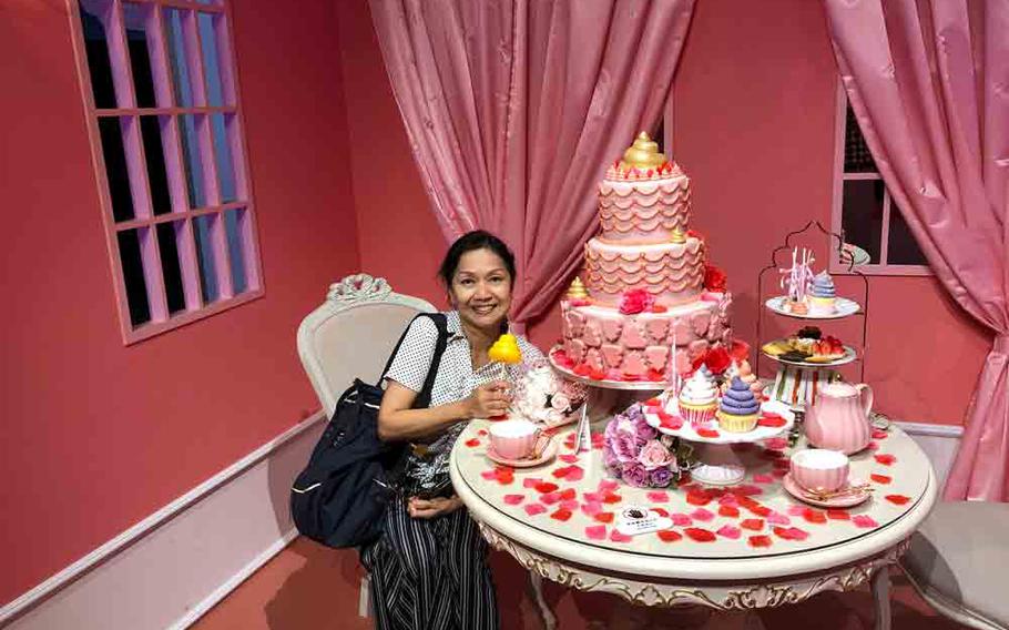 author’s wife holding a miniature unko and unko tea, cake set on the table