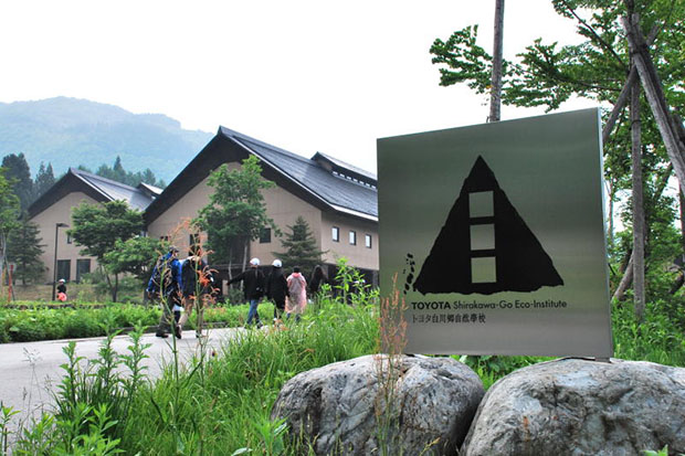 Tourists walk past signage of the Toyota Eco-Institute in the Shirakawa-go, a World Heritage site, in Japan. (Photo: Arusa Pisuthipan)