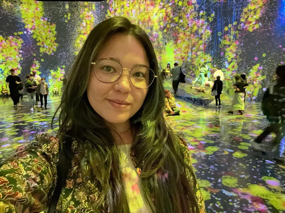 Author Ashley Probst smiling inside exhibit with colorful lights