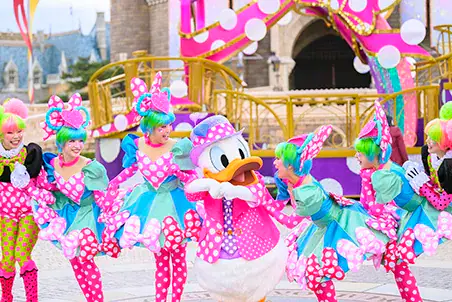 Donald Duck and dancers in polka-dot costumes perform at Tokyo Disney Resort's Minnie's Funderland, with no castle in view.