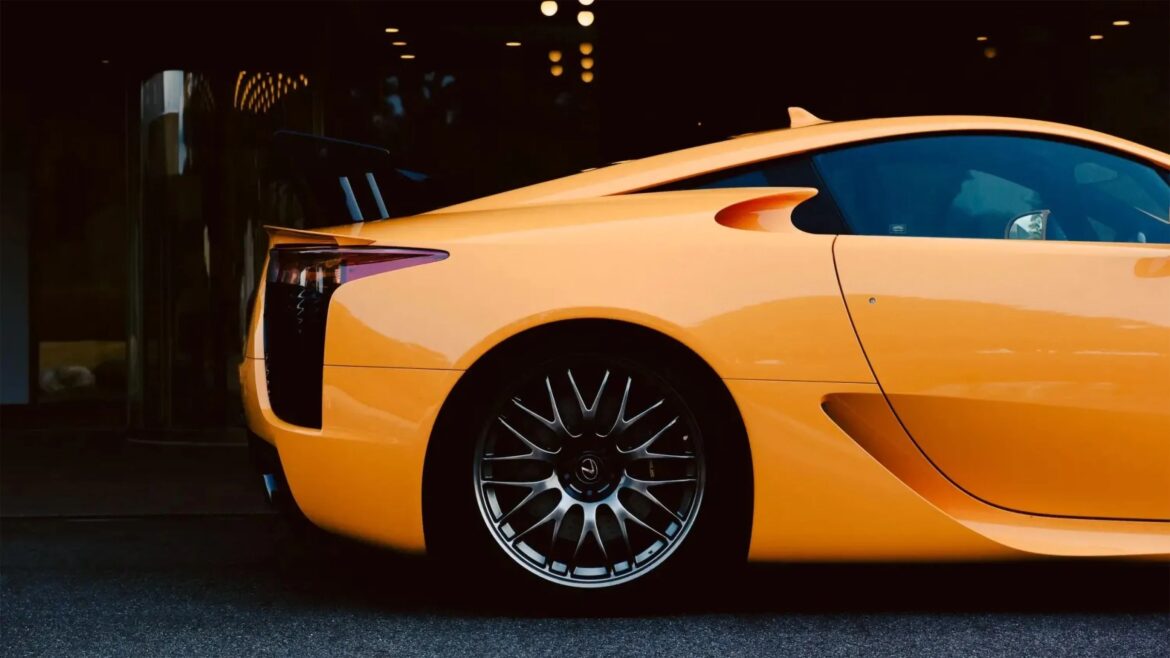 Rear side view of a yellow sports car with black multi-spoke alloy wheel and tinted windows.