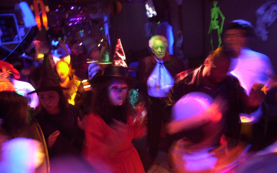 People dressed up in Halloween costumes dance during a party.