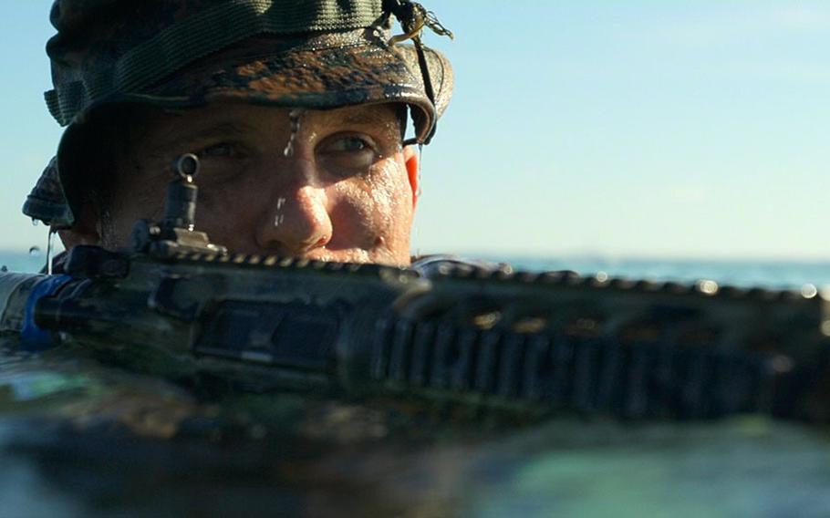 A U.S. Marine stands with his rifle in the water.